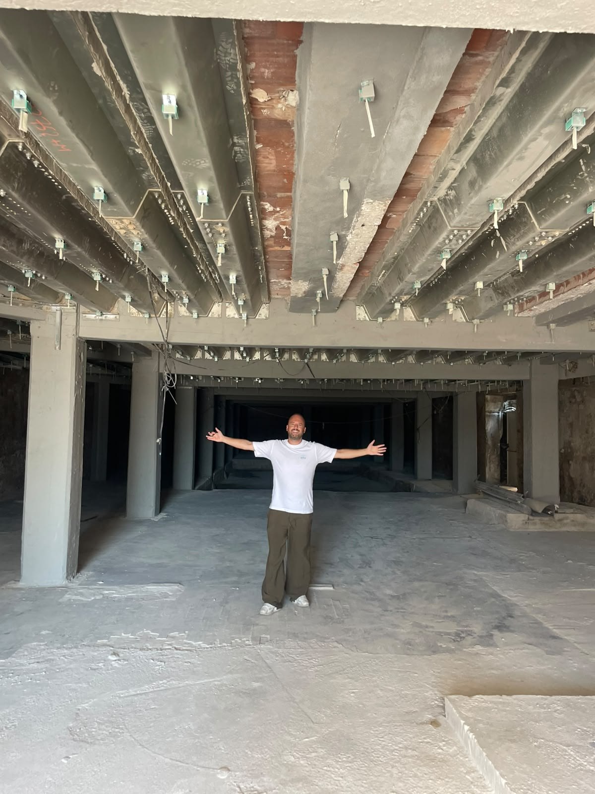 August 2026: the bare shell, steel bolted in, one man standing in the middle of it
