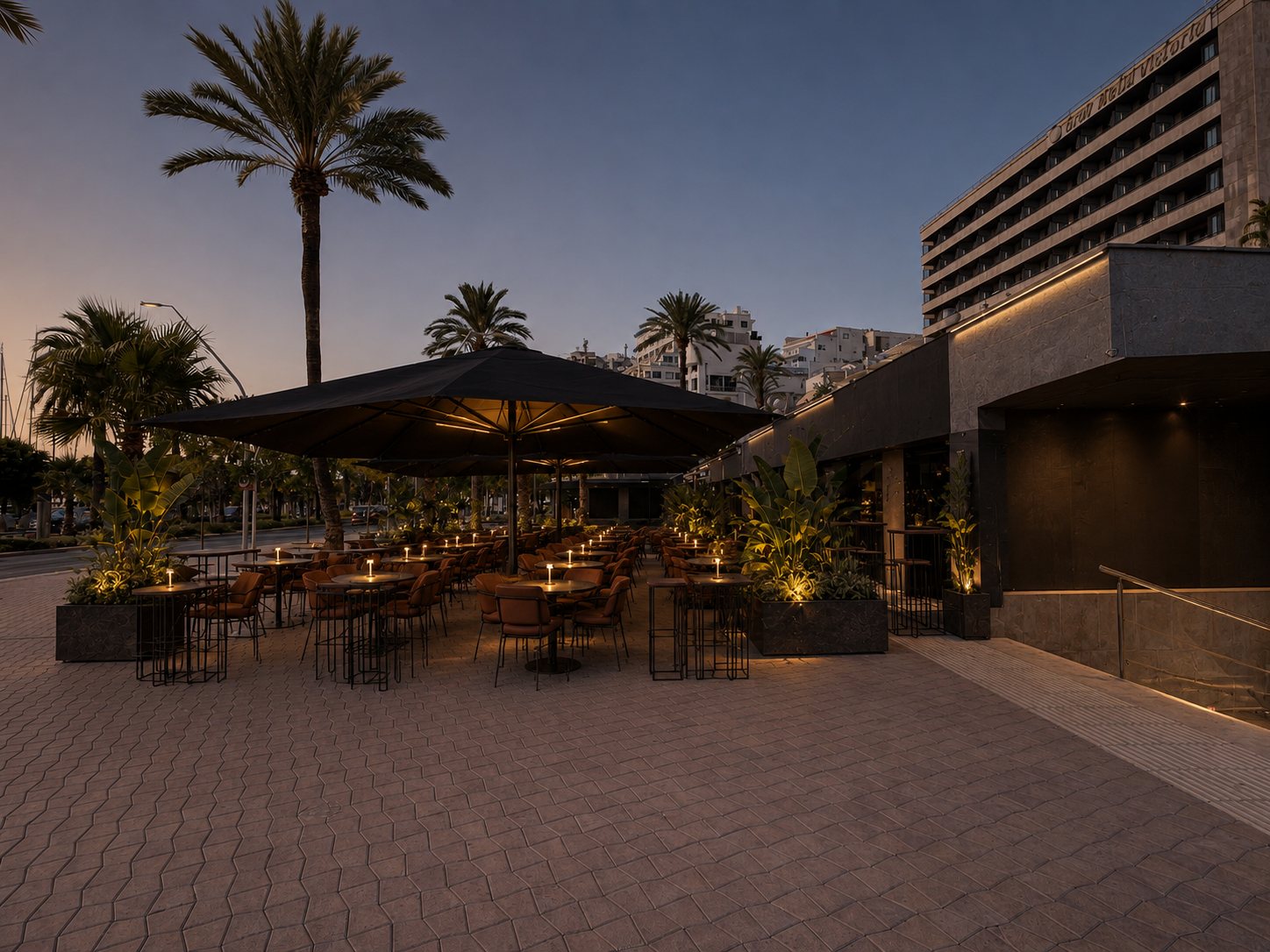 The DONDA terrace on the Paseo Marítimo at sunset, candles lit under the black parasols