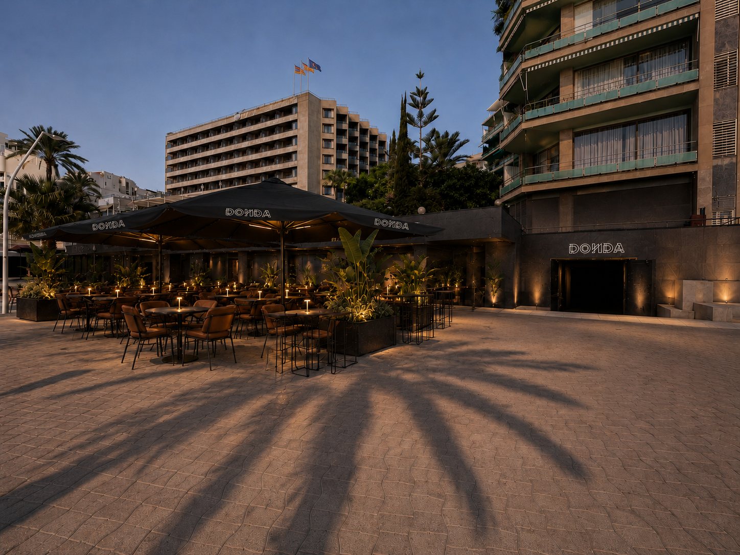 The DONDA frontage at blue hour: the neon over the entrance, the terrace lit alongside